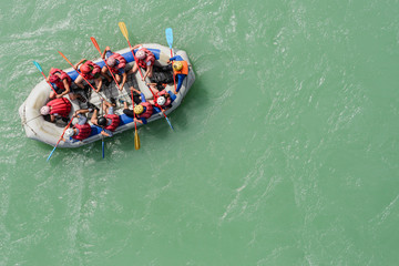 Top view of the boat with people rafting along the mountain river