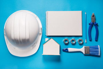 Construction tools and notebook on blue background