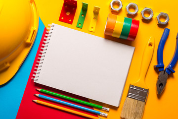 Construction tools and notebook on colorful background
