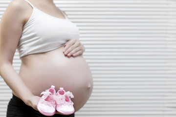 Pregnant woman showing baby shoes