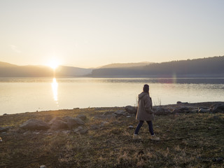 Solitary young woman taking a walk by a lake