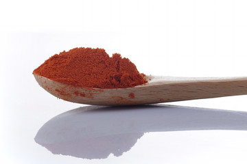 Chili powder with wooden spoon on white background