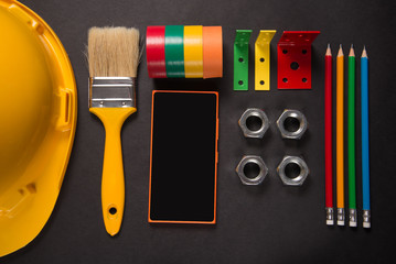 Construction tools and smart phone on black background