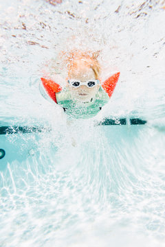 Young boy swimming under water in swimming pool, underwater view