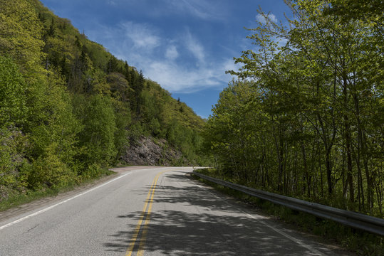Empty road amidst trees by hills, Dingwall, Cabot Trail, Cape Breton Highlands National Park, Cape Breton Island, Nova Scotia, Canada