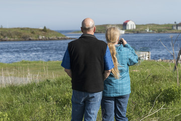 Rear view of couple taking picture with camera at riverbank, Cape Breton Island, Nova Scotia, Canada