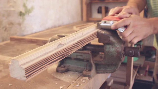 Carpenter's working on raw wood in little dusty workshop.