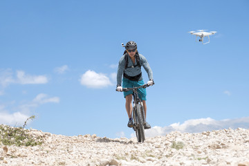 Obraz premium mountain biker with helmet camera followed by a drone