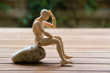 Man sitting on the stone, keeping his hand on the head