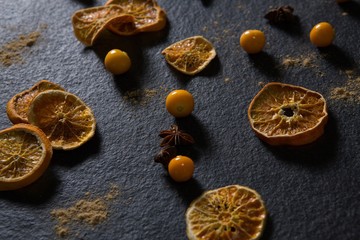 Dried orange with star anise and golden berries on black