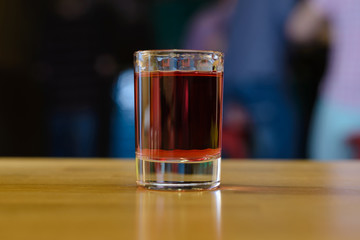 glass with red alcohol on a wooden table