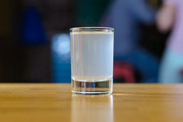 glass with white alcohol on a wooden table