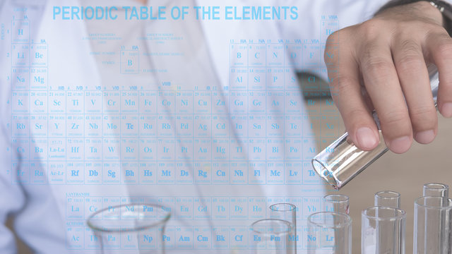 The double exposure image of the Asian young chemical scientists is working with the test tube in the laboratory overlay with the periodic table of elements.