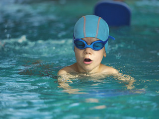 Happy little boy swimming in an indoor pool