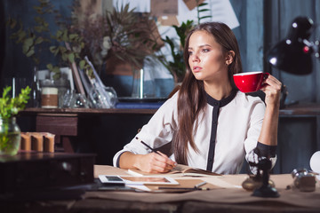 Young beautiful woman working with cup of coffee