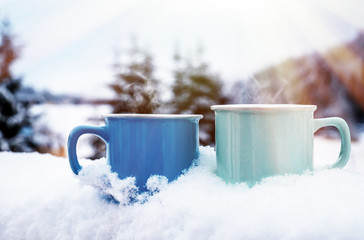 Cups of hot coffee on the snow. Christmas landscape.
