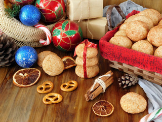 Biscuits with cinnamon surrounded by present boxes and Christmas attributes on a wooden background