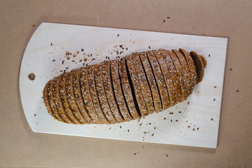 evenly sliced brown bread on wooden board for cutting