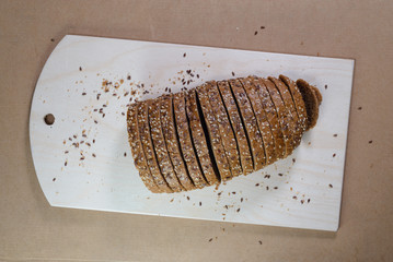 evenly sliced brown bread on wooden board for cutting