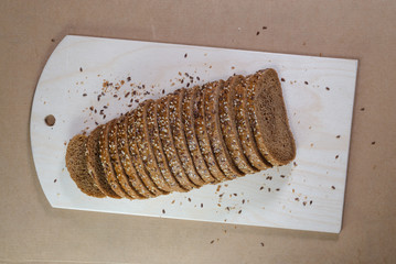evenly sliced brown bread on wooden board for cutting