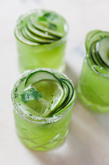 Cucumber and lime alcoholic cocktails on white marble surface