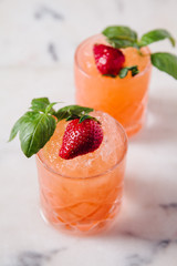 Refreshing strawberry and basil cocktails on white marble surface