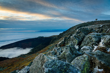 Cloud inversion from a mountain top - beautiful autumn landscape with thick blanket of rolling clouds at sunrise