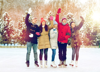 Obraz premium happy friends ice skating on rink outdoors