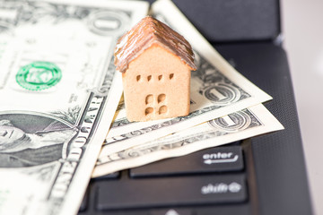 The cash and gold with the house model on laptop, the business finance and technology concept