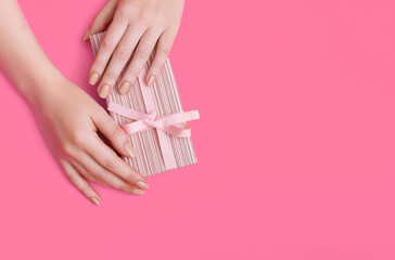 Woman hands holding present box with pink bow