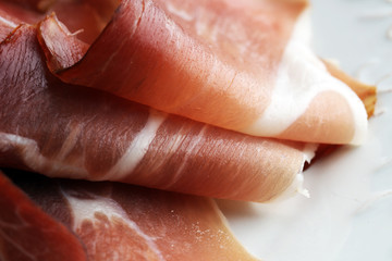 Italian prosciutto crudo or jamon. Raw ham on white dish.