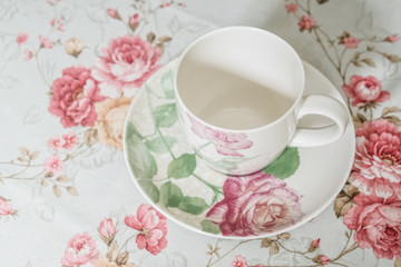 Obraz na płótnie Canvas cup on a floral tablecloth