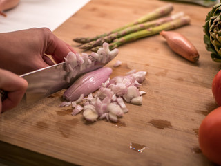 Chopping shallot onion on a wood cutting board