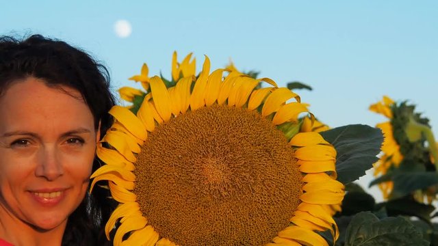 Happy girl with a big sunflower in the background of the moon. Face of woman close-up with flower of sunflower.