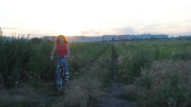 A girl outside the city rides a bicycle. Cyclist on the background of the city.