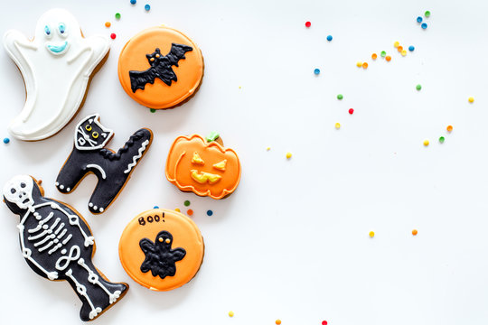 Halloween gingerbread cookies with pictures bat, pumpkin, skeleton, ghost on white background top view copyspace