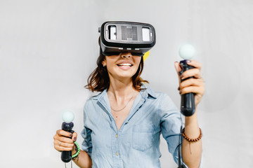 A woman enthusiastically playing or working in the helmet of virtual reality VR.