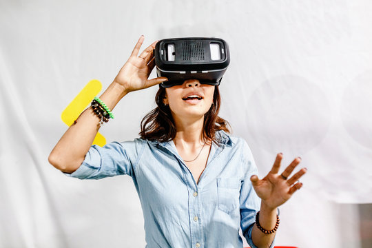 A woman enthusiastically playing or working in the helmet of virtual reality VR.