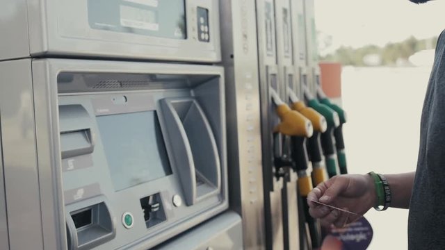 Man operating fuel pump payment kiosk, tourist pay card on gasoline station