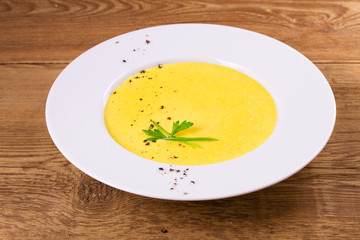 Creamy corn soup in white bowl, garnished with pepper, scallion and parsley, horizontal