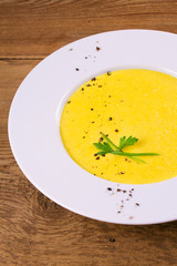 Creamy corn soup in white bowl, garnished with pepper, scallion and parsley. Vegetable soup, vertical