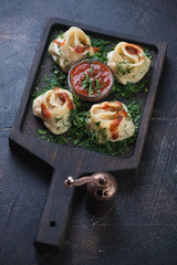 Wooden serving board with manti or steamed meat dumplings on a brown stone background, vertical shot