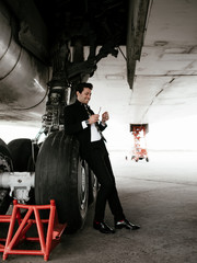 Serious handsome young man in the west and suit walk near plane on the airfield