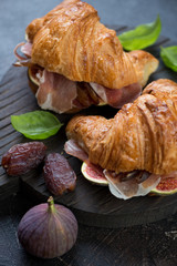 Close-up of croissants with prosciutto and fig fruits, selective focus, vertical shot