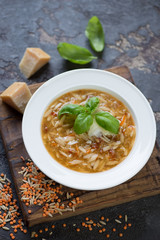 Plate of lentil and pasta soup with addition of parmesan on a wooden serving board, studio shot