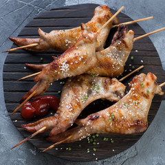 Black wooden serving board with grilled chicken wings on skewers, above view