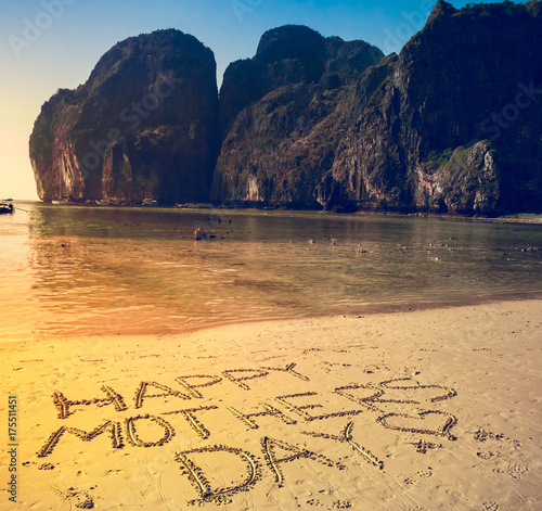 Happy Mother's Day written on the sand on a flat yellow beach. Mountains and clear ocean in the background. Phi-Phi Island, Thailand. Holiday, travel, sport, recreation. Retro vintage toning effect