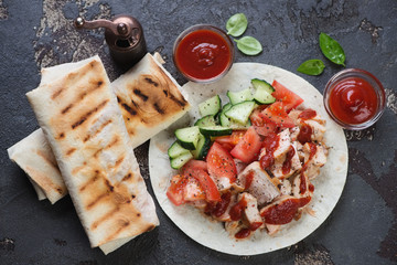 Shawarma with roasted chicken meat and vegetables, view from above on a brown stone background, horizontal shot