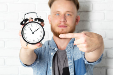 Young handsome man and clock on brick wall