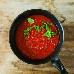 tomato sauce in a pan and fresh basil leaves